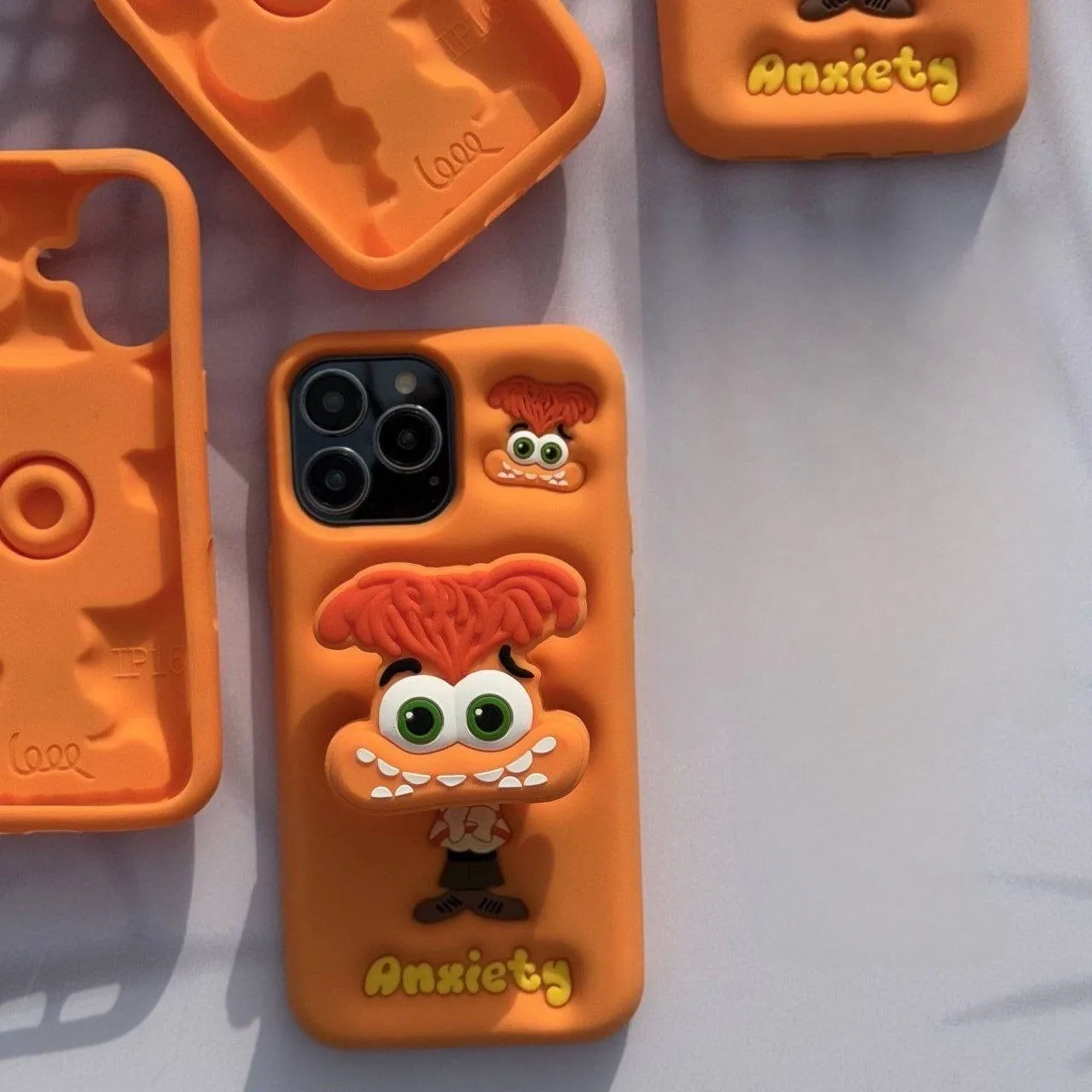 قاب گوشی آیفون سیلیکونی نارنجی طرح عروسکی شخصیت اضطراب با استند 